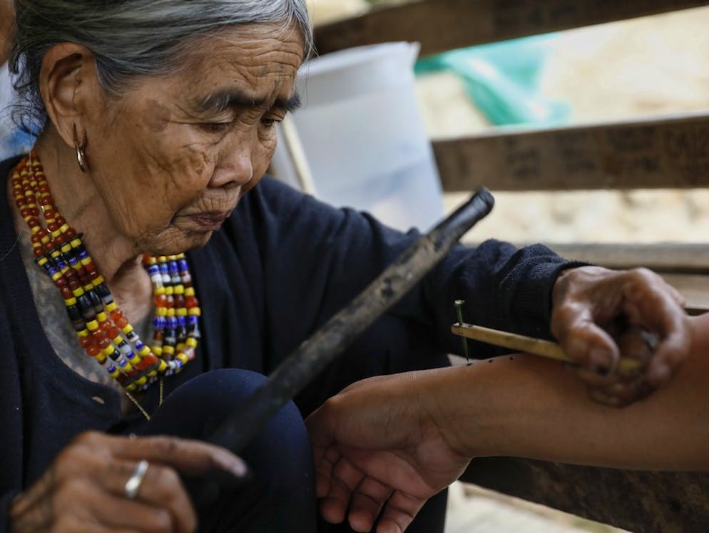 Whang Od, la tatuatrice centenaria. La filippina Whang Od (a sinistra) dice di avere 100 anni – e sarebbe dunque la più anziana artista Mambabatok vivente. Lei padroneggia l'arte del tatuaggio tribale tradizionale, che un tempo era riservato ai cacciatori di teste e ai guerrieri. Ormai, i suoi clienti sono soprattutto turisti.