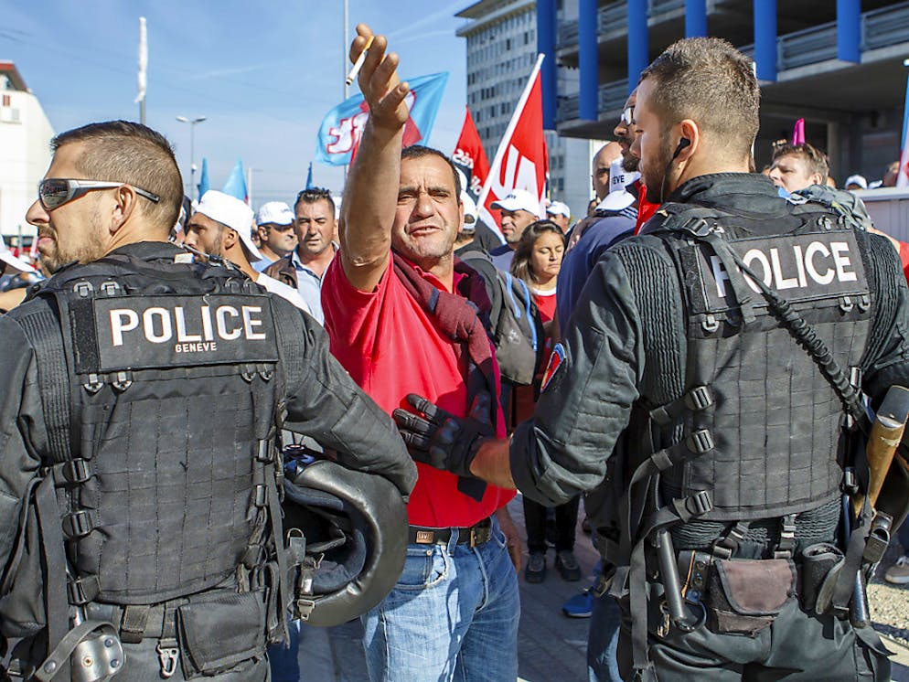 La police genevoise barre l'accès à un chantier face à des ouvriers du bâtiment en colère.