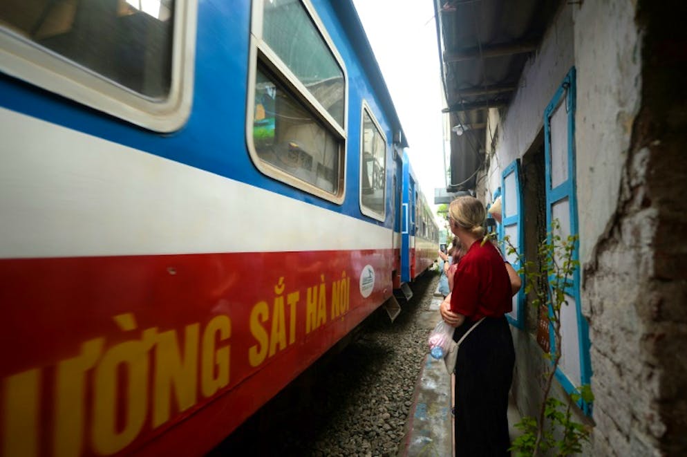 Un train passe devant des touristes dans le vieux quartier de Hanoï, le 20 octobre 2018