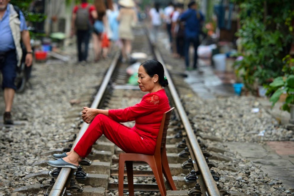 Une Vietnamienne assise sur une chaise posés sur les rails du chemin de fer dans le vieux quartier de Hanoï le 20 octobre 2018.