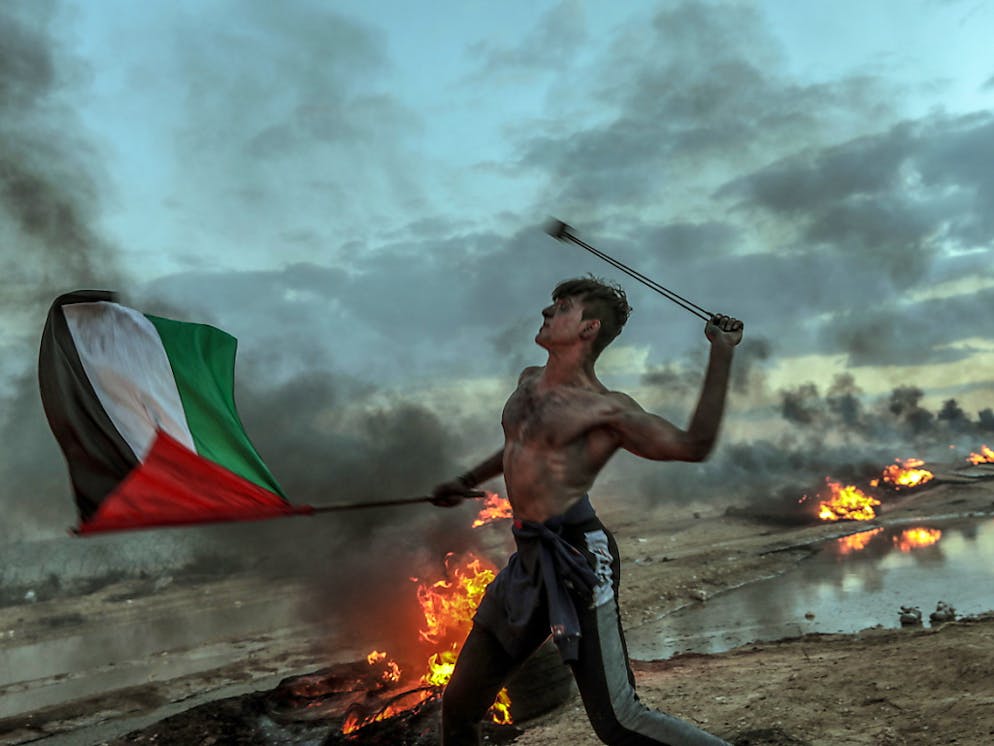 Les Palestiniens manifestent le long de la barrière frontalière séparant Gaza d'Israël au moins une fois par semaine depuis le 30 mars, ce qui provoque certains jours des accrochages. Ici un manifestant en train de lancer vendredi une pierre en direction des troupes israéliennes.