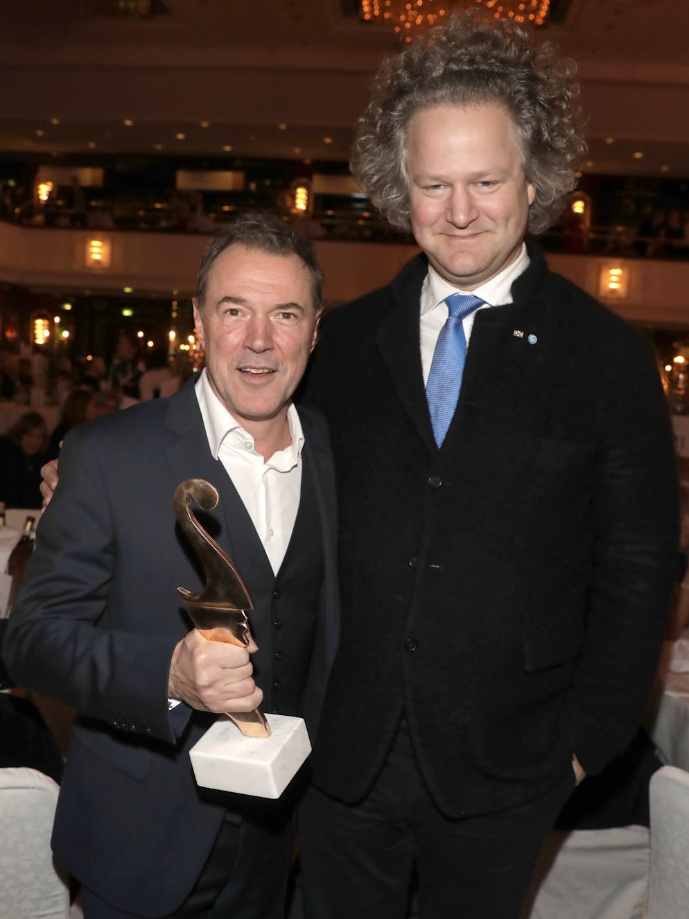 Sebastian Koch: Die Bilder. Preisträger: 2018 erhielt Sebastian Koch den «Premio Bacco» auf der Berlinale. Den Preis verleihen italienische Filmkritiker und Korrespondenten an italienische und deutsche Schauspieler oder Filmpersönlichkeiten für herausragende Leistungen. Überreicht wurde ihm der Preis von Regisseur Florian Henckel von Donnersmarck (r.) mit dem er auch «Werk ohne Autor» drehte.