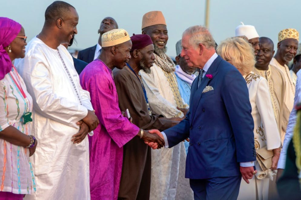 Le prince Charles et son épouse Camilla saluent des responsables de la Gambie à leur arrivée à l'aéroport de Banjul le 31 octobre 2018