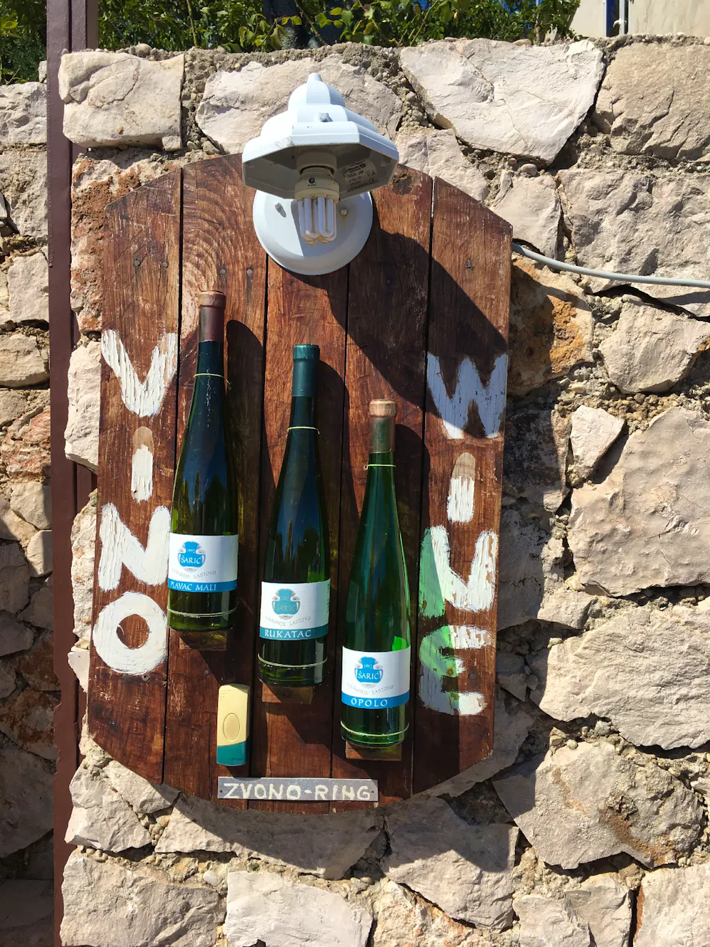 7 endroits à visiter en Croatie. Accueillants: trois bouteilles de vin décorent la sonnette d’une porte sur laquelle on peut lire «ring».