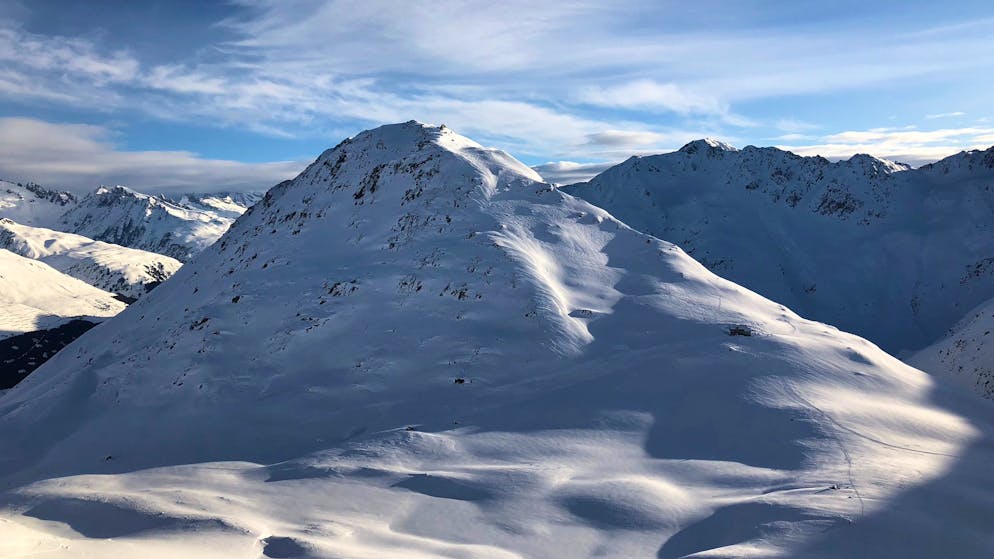Skitour im Bündner Oberland. Der nächste Morgen: Nach einer kurzen Abfahrt von der SAC-Hütte in den Talboden haben wir die Felle montiert und sind losgezogen. Hier befinden wir uns bereits auf etwa 2600 Metern Höhe. Der Piz Cavradi, der zweite Gipfel dieses Tages, ragt hinter der Maighelshütte in die Höhe. 