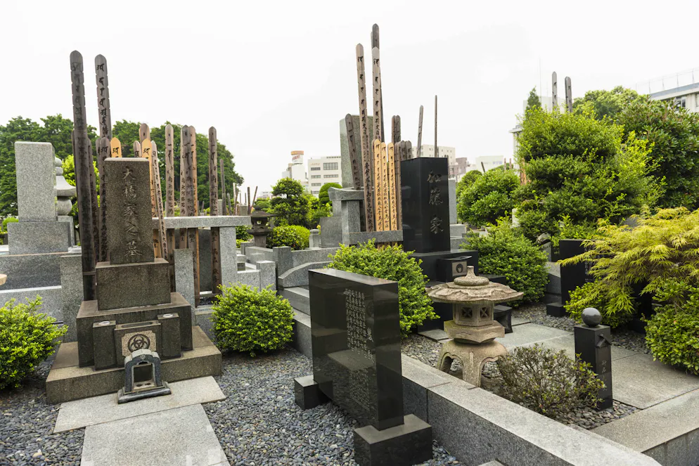 Printemps des cimetières : 6 sites à visiter dans le monde. Tokyo, Japan - August 17, 2014: Yanaka Cemetery, view on some graves from black marble and wooden pools with japanese writing. Green bushes around.