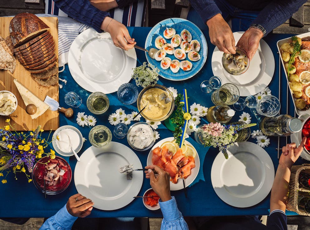 Mittsommerfest in Schweden: Blüten, Schnaps und lange Nächte. Wer müde wird stärkt sich an den üppigen Buffets mit eingelegtem Hering, Lachs, Kartoffeln, Ei und Schnaps. Denn am Mittsommer wird die Nacht buchstäblich zum Tag.