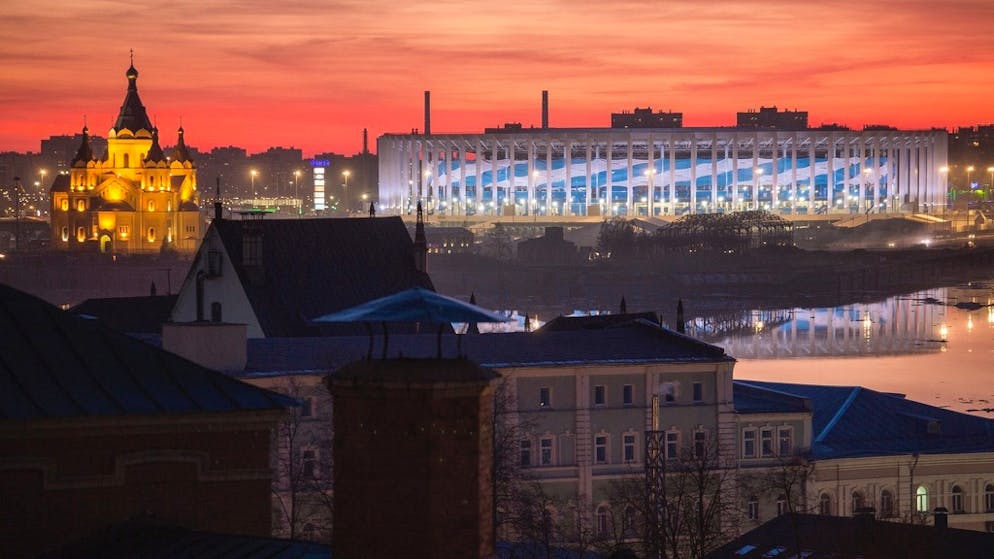 Lo stadio risplende di blu nella luce serale. Sinistra: La Cattedrale Alexandr Nevskij.