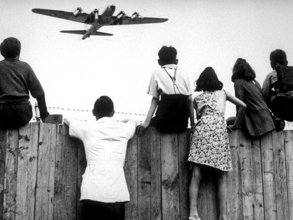 Blocco di Berlino: 70 anni fa, i «Rosinenbomber» sorvolavano la città. È il 1948: alcuni ragazzini di Berlino sono seduti sulla recinzione dell'aeroporto di Berlino-Tempelhof mentre un bombardiere dell'aviazione americana si appresta ad atterrare. L'aereo fa parte del ponte avviato per fornire merci a Berlino Ovest, dopo che l'accesso era stato bloccato dalla truppe sovietiche.