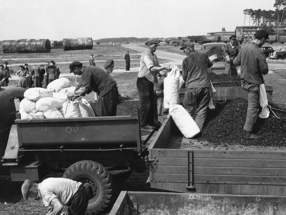 Blocco di Berlino: 70 anni fa, i «Rosinenbomber» sorvolavano la città. Alcuni soldati intenti a scaricare le merci.