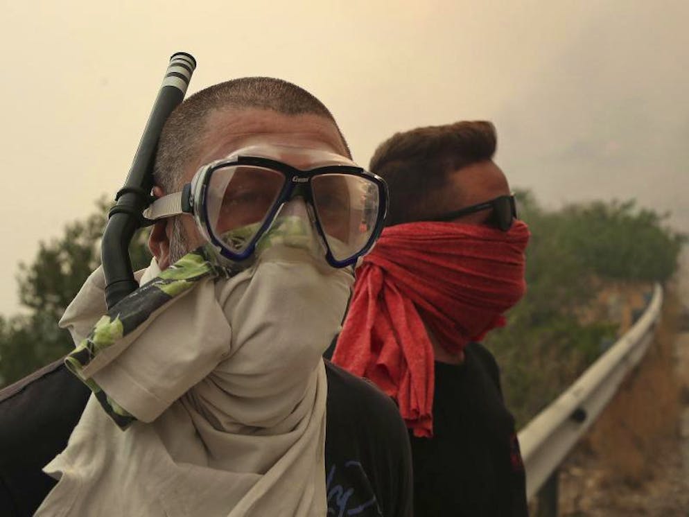 Brände in Griechenland. Tücher und Schnorchel bieten Schutz vor dem beissenden Qualm im griechischen Kineta.  