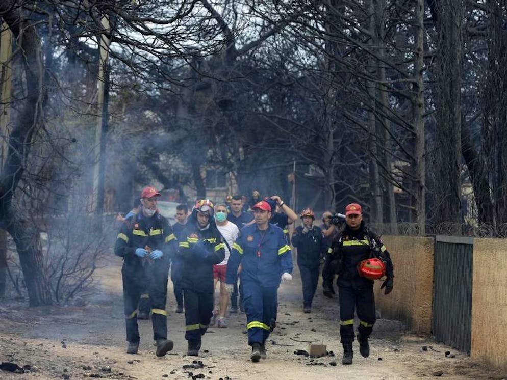 Brände in Griechenland. Feuerwehrleute inspizieren ein verbranntes Gebiet.  