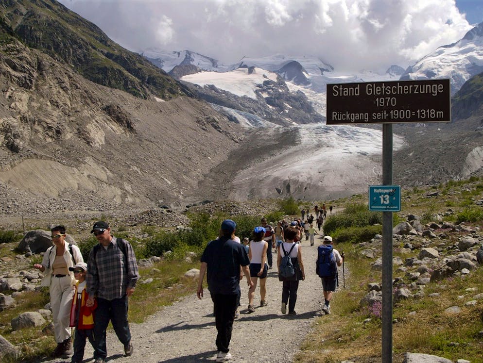 Wanderer pilgern im Juli 2003 zur Abkühlung in grossen Scharen zum Morteratschgletscher bei Pontresina im Oberengadin. Jahr für Jahr wird der Fussmarsch um einige Minuten länger. Wie bei praktisch allen Schweizer Gletschern schwinden auch die Eismassen des Morteratschgletschers in besorgniserregendem Tempo.