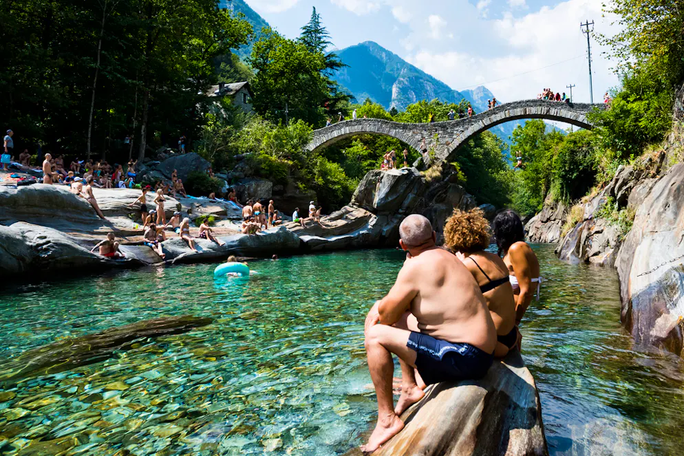 Alcune persone fanno il bagno e prendono il sole sulle rive del torrente Verzasca.