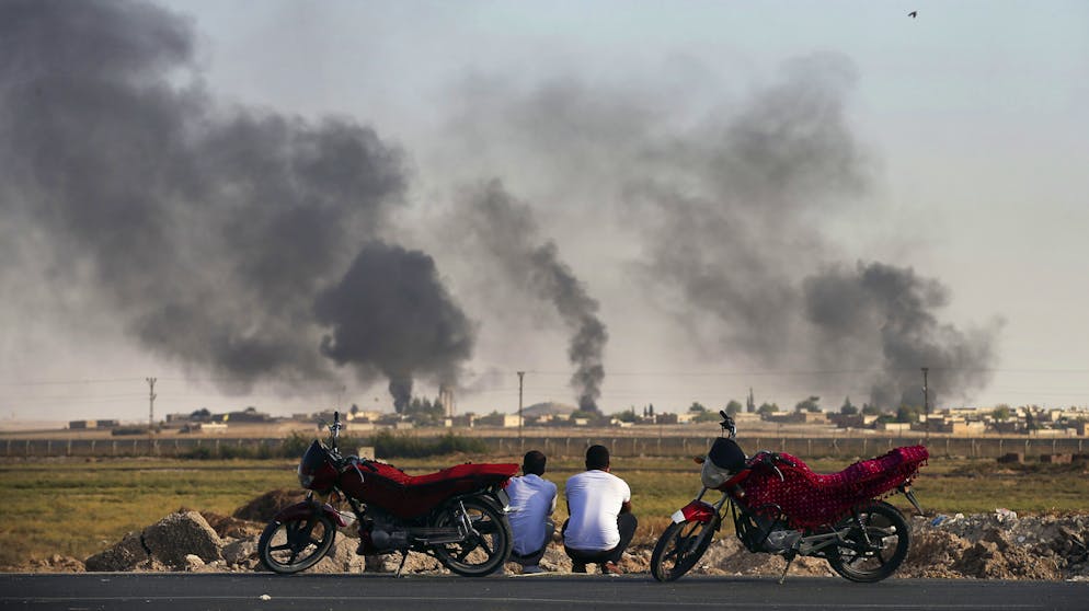 Männer beobachten am 10. Oktober von der türkischen Akcakale-Provinz aus in Syrien einschlagende Granaten.