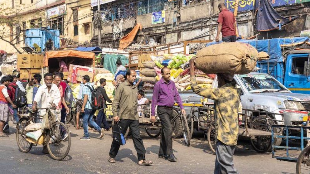 Kalkutta – bunte Metropole am Ganges. Kalkutta ist eine belebte Stadt. Nahe der Howrah Bridge teilen sich Fussgänger, Autofahrer und Händler die Strasse. 