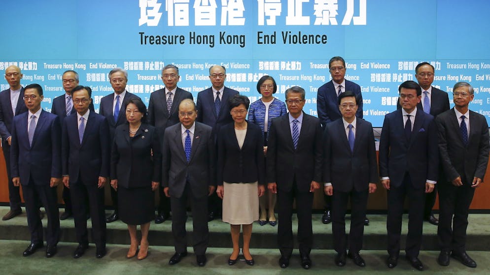 Regierung Hongkongs verbietet Vermummung. Hongkongs Regierungschefin Carrie Lam trat mit ihrem ganzen Kabinett vor die Medien, um Geschlossenheit zu demonstrieren.