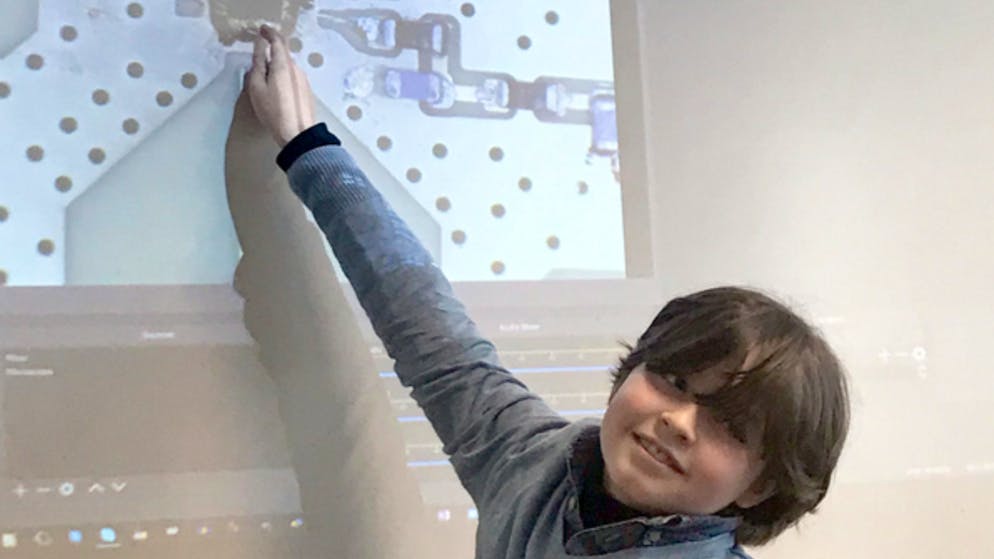 Laurent im Arbeitszimmer seines Professors vor einer Vergrösserung seines Examen-Projektes: Der kluge Kopf deutet auf einen von ihm entwickelten Mikrochip, mit dem Reaktionen von Gehirnzellen gemessen werden. 