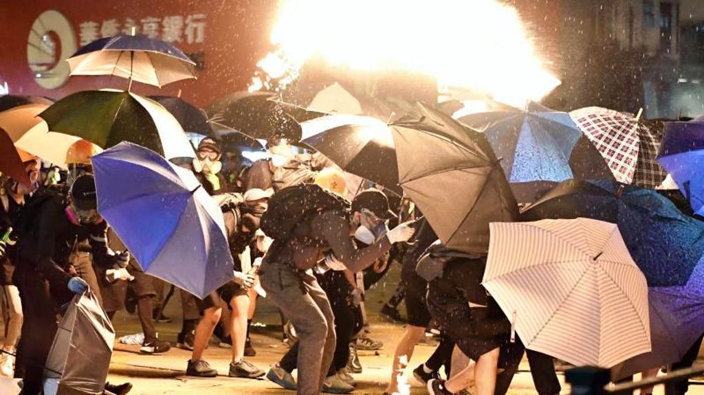 Protection contre le feu: des manifestants s’abritent sous des parapluies près de l’université polytechnique de Hong Kong.