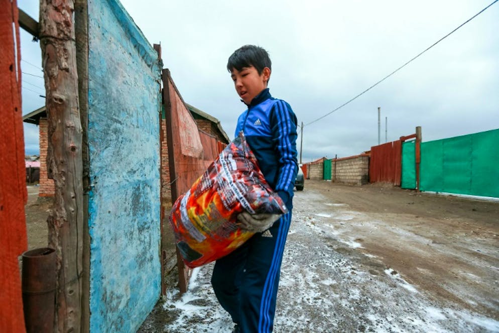 Dans cette photo du 19 octobre 2019, un garçon porte un sac de charbon sans fumée. Pour purifier l'atmosphère, Oulan-Bator encourage les familles à utiliser du charbon sans fumée, mais cette source de chaleur a déjà tué huit fois dans la capitale mongole.