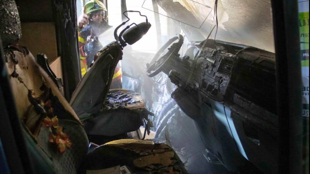 Ein Feuerwehrmann löscht in Zug die letzten Glutnester in einem Lieferwagen.