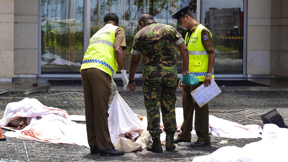 Fast 300 Tote nach Explosionen in Kirchen und Hotels in Sri Lanka. Polizisten untersuchen die Leichen der Anschlagsopfer.