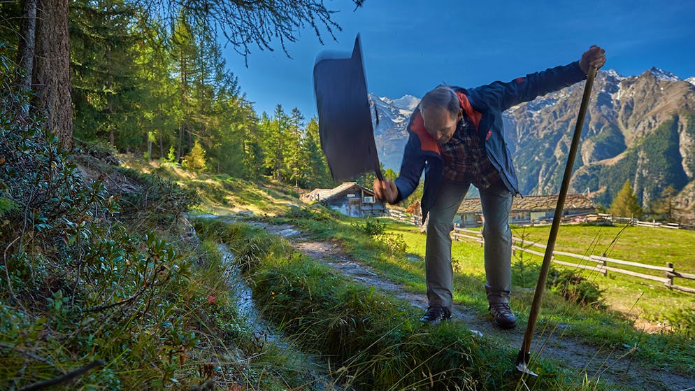 Wasserschloss Schweiz – alles im Fluss. Als Kind waren die Arbeiten an den Leitungen lästige Pflicht, heute sind Ruppens Hobby. Mit einem beherzten Hieb der «Wasserplatta» staut er die Suone ...