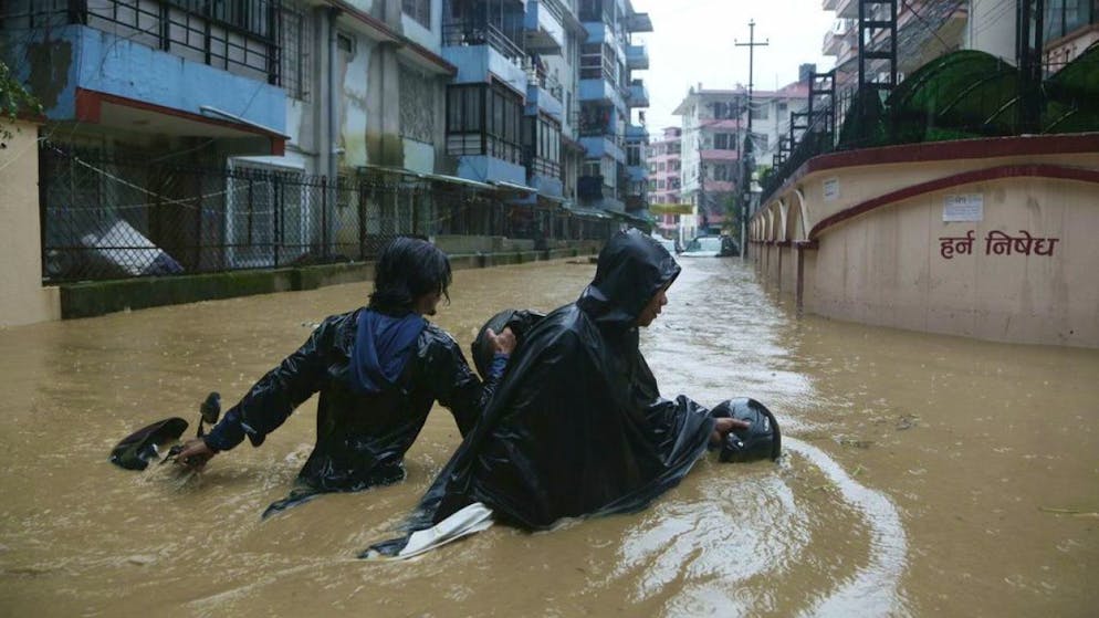 Nepalesen waten mit ihrem Motorrad durch die überfluteten Strassen der Hauptstadt Kathmandu.