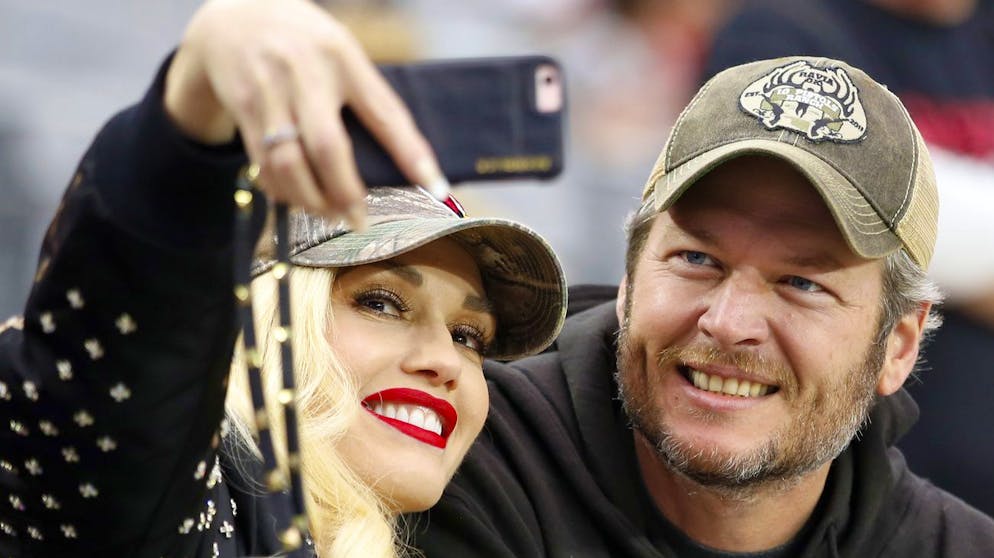 Singers Gwen Stephani and Blake Shelton take a selfie from the sidelines prior to an NFL football game between the Green Bay Packers and the Arizona Cardinals, Sunday, Dec. 27, 2015, in Glendale, Ariz. (AP Photo/Jeff Haynes)