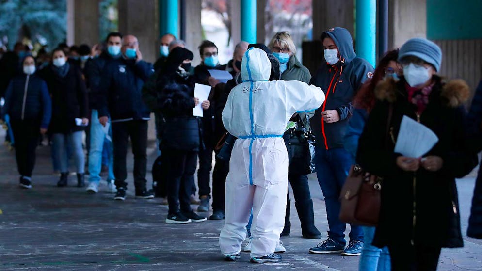 Menschen stehen vor einer Corona-Schnelltest-Einrichtung in Bozen Schlange. Foto: Antonio Calanni/AP/dpa