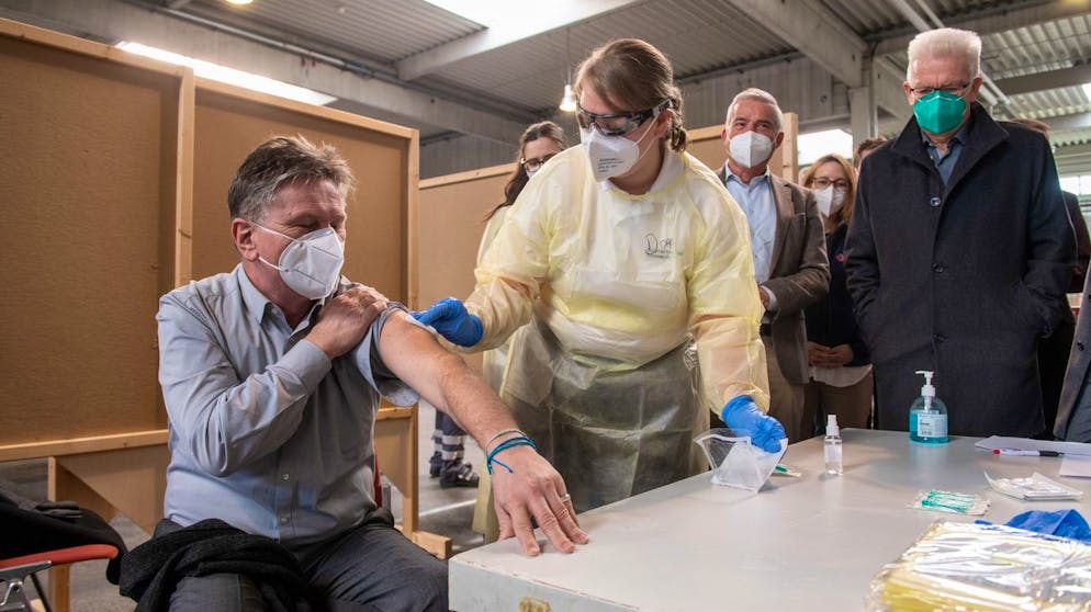 Baden-Württembergs Sozialminister Manne Mucha (Bündnis 90/Die Grünen) lässt sich am 21. November 2020 im Messezentrum in Ulm von Notfallsanitäterin Dorothea Gansloser den Ablauf einer Coronaimpfung demonstrieren.