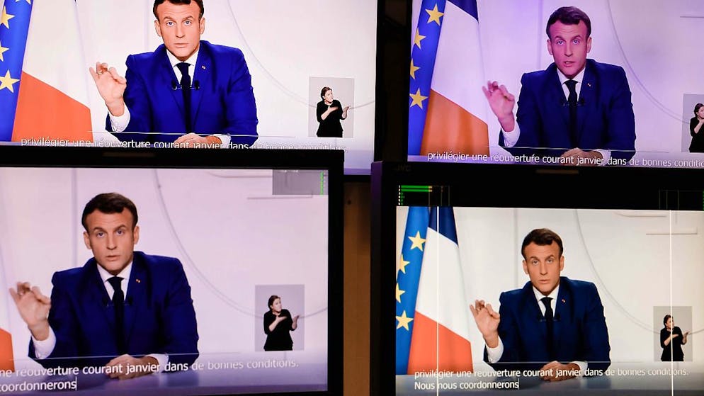 Die abfotografierten Bildschirme zeigen Emmanuel Macron, Präsident von Frankreich, der eine Fernsehansprache an die Nation zur aktuellen Corona-Lage hält. Angesichts einer verbesserten Corona-Lage hat Frankreichs Präsident Macron erste Lockerungen der strengen Beschränkungen im Land angekündigt. Foto: Thomas Coex/AFP/dpa – ACHTUNG: Nur zur redaktionellen Verwendung im Zusammenhang mit der aktuellen Berichterstattung und nur mit vollständiger Nennung des vorstehenden Credits