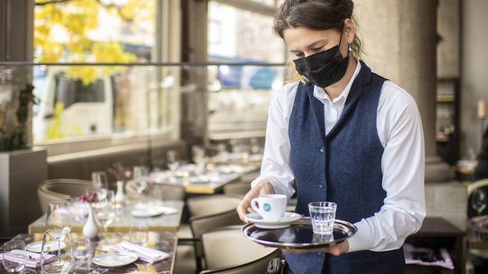 Eine Frau mit Atemschutzmaske serviert einen Espresso im Restaurant Terrasse, aufgenommen am Dienstag, 27. Oktober 2020 in Zuerich. (KEYSTONE/Ennio Leanza)