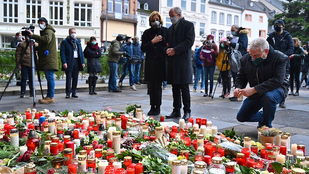 Malu Dreyer (SPD), Ministerpräsidentin von Rheinland-Pfalz, und ihr Ehemann Klaus Jensen stehen vor Blumen und Kerzen, die vor der Porta Nigra im Gedenken der Opfer der Amokfahrt eines 51-jährigen Mannes durch die Innenstadt niedergelegt wurden. Foto: Harald Tittel/dpa