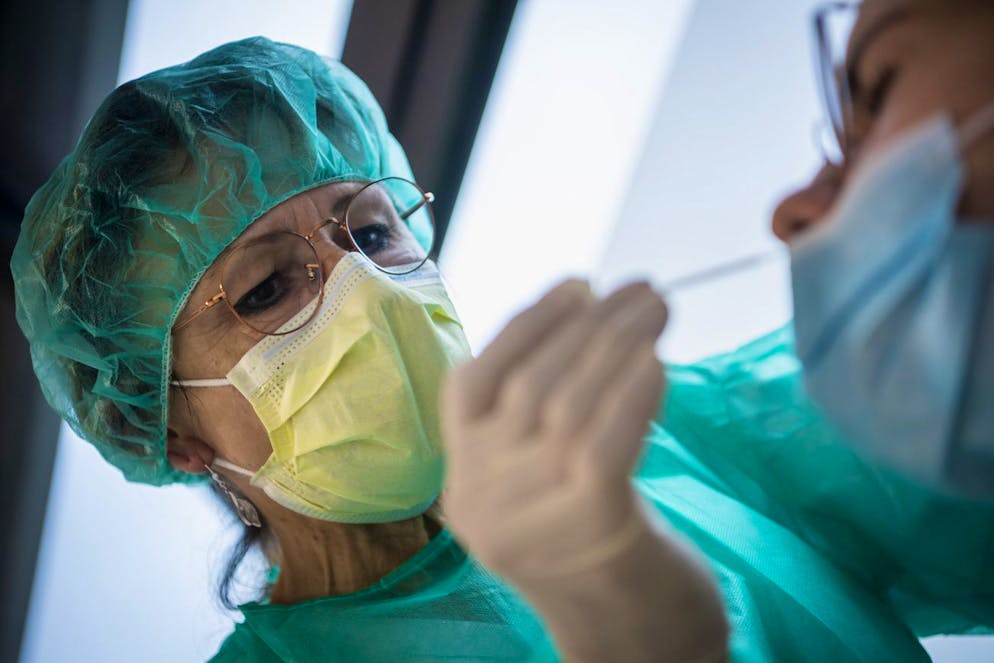 Une infirmiere pratique un frottis a une patiente dans le Centre de Depistage Covid du Jura lors de la crise du Coronavirus (Covid-19) le vendredi 23 octobre 2020 a Courroux entre Delemont et Courrendlin. Les cantons romands annoncent de nouvelles mesures plus strictes pour endiguer la propagation du coronavirus. Dans le Jura, les bars et restaurants devront fermer a 22h00. (KEYSTONE/Jean-Christophe Bott)