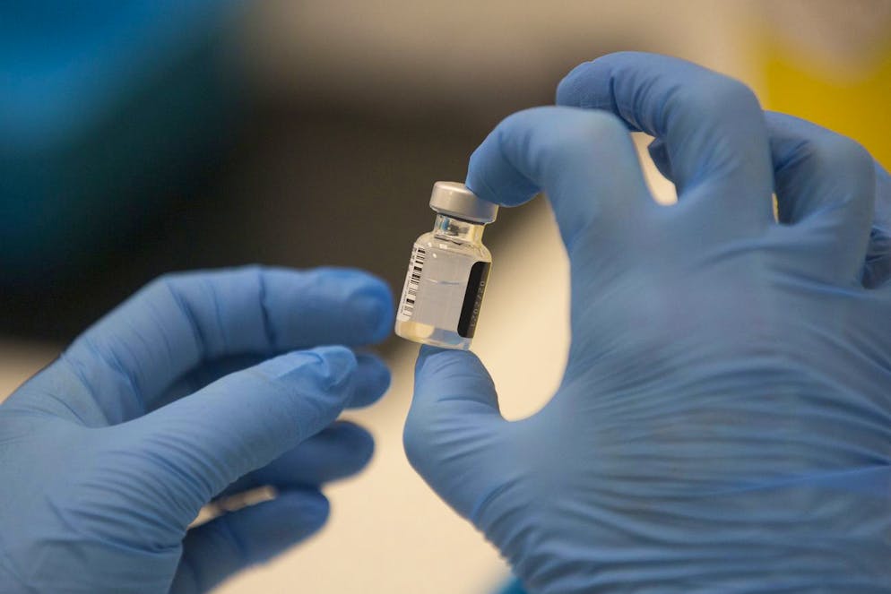 A worker holds a bottle of the Pfizer-BioNTech COVID-19 vaccine, as the mass public vaccination program gets underway at Southmead Hospital in Bristol, England, Tuesday Dec. 8, 2020. The United Kingdom, one of the countries hardest hit by the coronavirus, is beginning its vaccination campaign to inoculate people against the COVID-19 virus. (Graeme Robertson/Pool via AP)