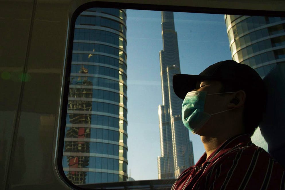 A commuter wearing a face mask to help curb the spread of the coronavirus, sleeps aboard the driverless Metro as it passes the Burj Khalifa, the world's tallest building, in Dubai, United Arab Emirates, Sunday, April 26, 2020. Dubai resumed service on its driverless Metro system and normal fares in its many taxicabs Sunday as the UAE tries to slowly reopen amid the coronavirus pandemic. (AP Photo/Jon Gambrell)