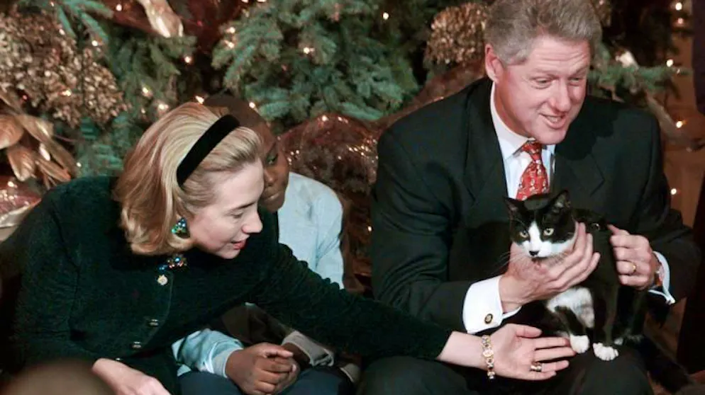 Bill Clinton 1996 mit Katze Socks auf dem Schoss, daneben die damalige First Lady Hillary Clinton.