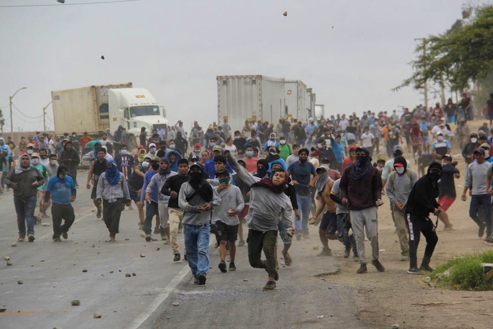 epa08912105 Agro-industrial workers throw stones as they clash with the police during a protest in Viru, some 510km north of Lima, Peru, 30 December 2020. At least two people, including a minor, died in Peru during fresh protests of workers in the agro-industrial sector, unhappy with the new agrarian labor regime approved the day before by Congress. EPA/IVAN ORBEGOSO