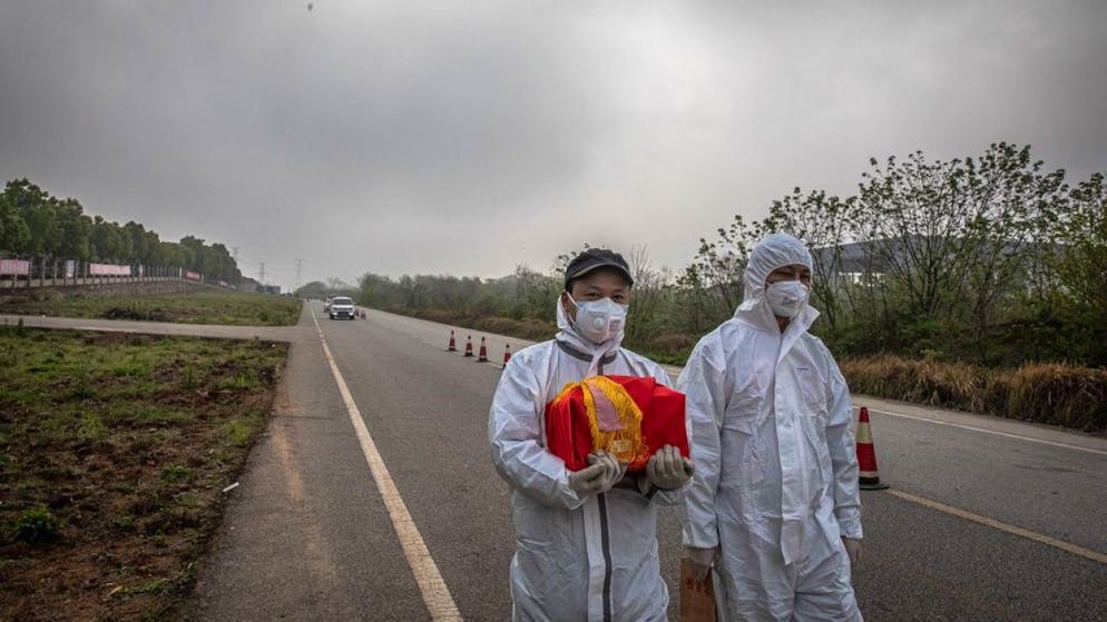Ein Paar in Wuhan trägt die Asche eines Verwandten nach Hause. Die drastischen Sperrmassnahmen in Wuhan, welches als Epizentrum der Covid-19-Epidemie gilt, hat genützt, wie eine Studie beweist.