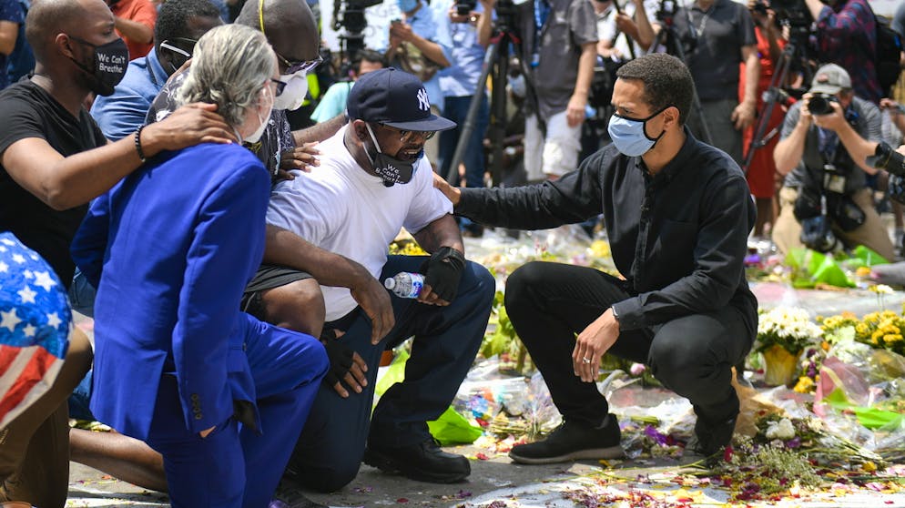 USA: Unruhen nach dem Tod von George Floyd. Die Polizei hat Floyd angehalten, weil er mit einer gefälschten Banknote bezahlt haben soll. Der Bruder des Opfers (im weissen T-Shirt) trauert an der Todesstelle in Minneapolis.