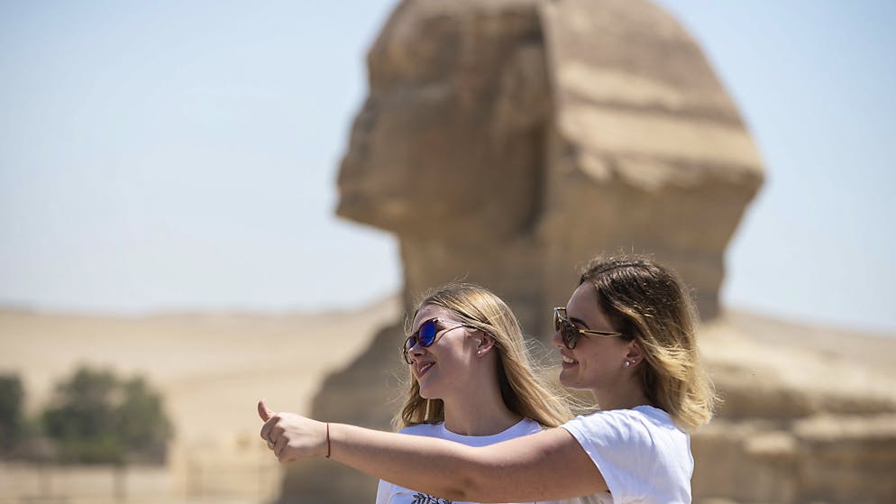 Due turiste in posa davanti alla Sfinge, nel complesso delle piramidi di Giza, riaperte oggi al pubblico