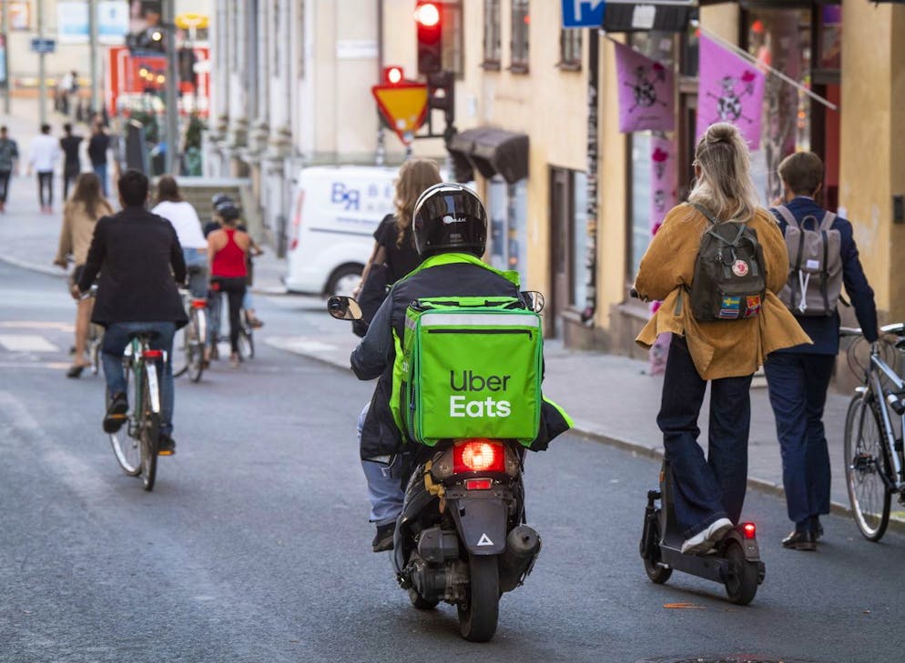 epa08615305 A moped delivery courier of Ubereats food delivery company rides among bicycles and electric scooters along a car free street street in the Sodermalm neighbourhood of Stockholm, Sweden, 20 August 2020. EPA/Fredrik Sandberg SWEDEN OUT