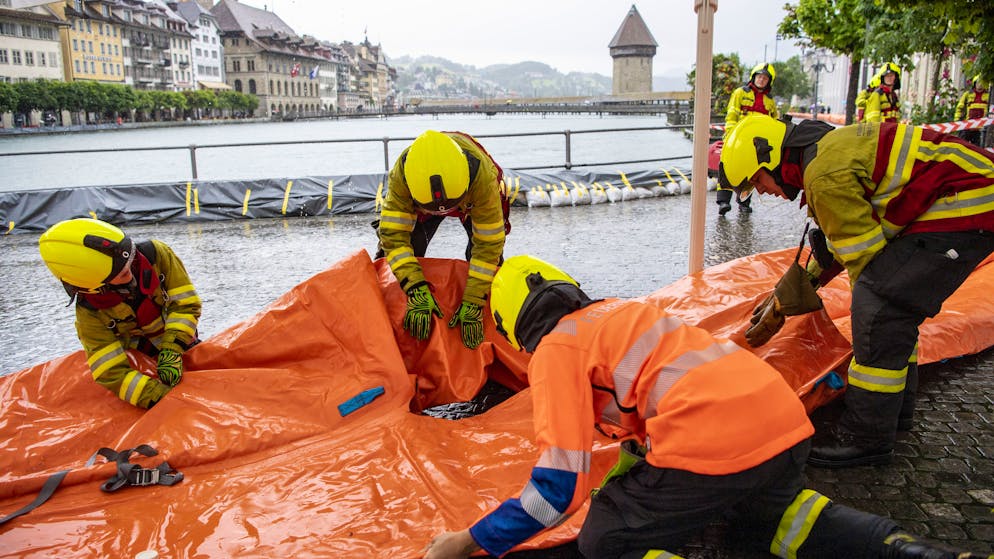 Die Feuerwehr der Stadt Luzern sichert die Bahnhofstrasse entlang der Reuss mit Schutzschlaeuchen aufgrund der angekuendigten Regenfaelle der naechsten Tage, am Dienstag, 13. Juli 2021, in Luzern. Der Wasserspiegel des Vierwaldstaettersees ist bedrohlich hoch angestiegen und es muss in den naechsten Tagen mit Ueberschwemmungen gerechnet werden. (KEYSTONE/Urs Flueeler)