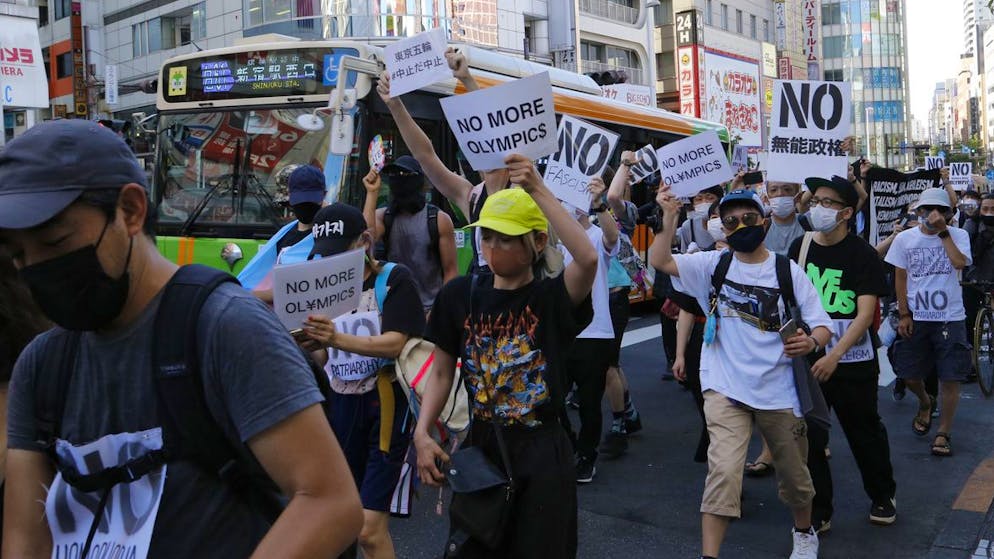 People march in Tokyo's Shinjuku shopping district Sunday, July 18, 2021, to protest against the Olympics starting from July 23. They held signs that said No Olympics.(AP Photo/Yuri Kageyama)