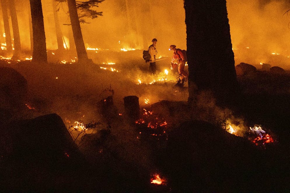 Un pompier utilise une torche goutte à goutte pour enflammer la végétation tout en essayant d'empêcher l'incendie de Dixie de se propager dans la forêt nationale de Lassen, en Californie, le lundi 26 juillet 2021.
