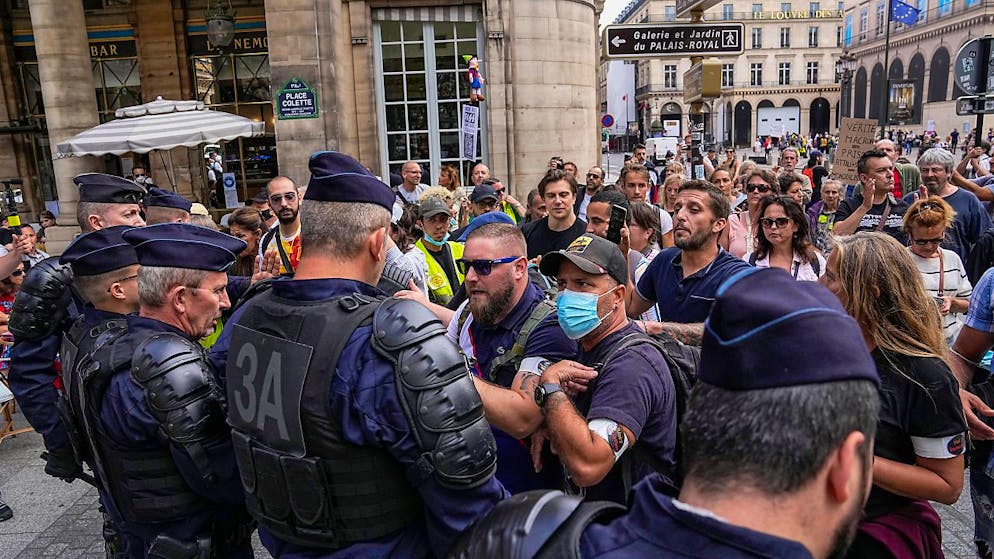 Demonstranten stehen bei einem Protest gegen den neuen Gesundheitspass in Paris Polizisten gegenüber. Foto: Michel Euler/AP/dpa