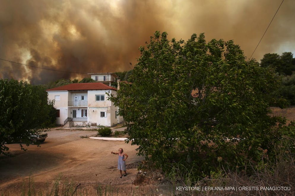 epa09397651 A woman speaks to media during a wildfire in Viliza village in the area of Ancient Olympia, Peloponnese, Greece, 05 August 2021. Fires continued to rage in Olympia, in the Peloponnese, where more settlements had to be evacuated during the night. The municipality of Ancient Olympia, which includes the original site of the Olympic Games, has been evacuated since 04 August. Meanwhile two fire-fighting aircraft are expected to arrive from Sweden, while 81 French fire-fighters are due to arrive on 05 August following Greece's request for assistance via the European Civil Protection Mechanism. A team of fire-fighters from Cyprus and two Cypriot fire-fighting aircraft have been in Greece since the day before. EPA/ORESTIS PANAGIOTOU