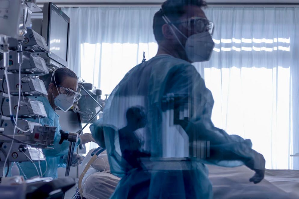 Medical workers treat a patient with Covid-19 in the intensive care unit at the the University Hospital (CHUV) during the coronavirus disease (COVID-19) outbreak in Lausanne, Switzerland, Friday, November 6, 2020. The number of Covid-19 hospitalisations and capacity continues to be a major concern in Switzerland. (KEYSTONE/Jean-Christophe Bott) Des soignants effectuent des soins sur un patient atteint de Covid-19 dans l'unite des soins intensifs du Centre Hospitalier Universitaire Vaudois, CHUV, lors de la crise du Coronavirus (Covid-19) le vendredi 6 novembre 2020 a Lausanne. (KEYSTONE/Jean-Christophe Bott)