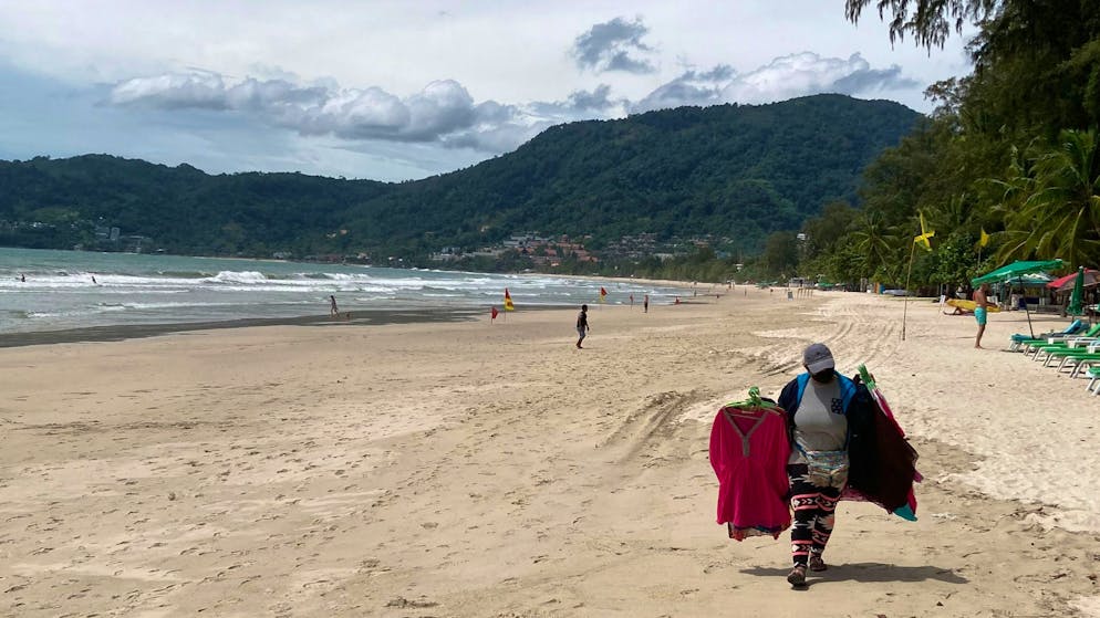 Keine Party in Thailand. Eine Verkäuferin geht am berühmten Strand Patong Beach auf der Insel Phuket. Trotz des Corona-Modellprojekts «Sandbox» zur Wiederbelebung des Tourismus bleiben die Liegen zumeist leer.